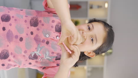 Vertical-video-of-Girl-child-making-heart-sign-at-camera.